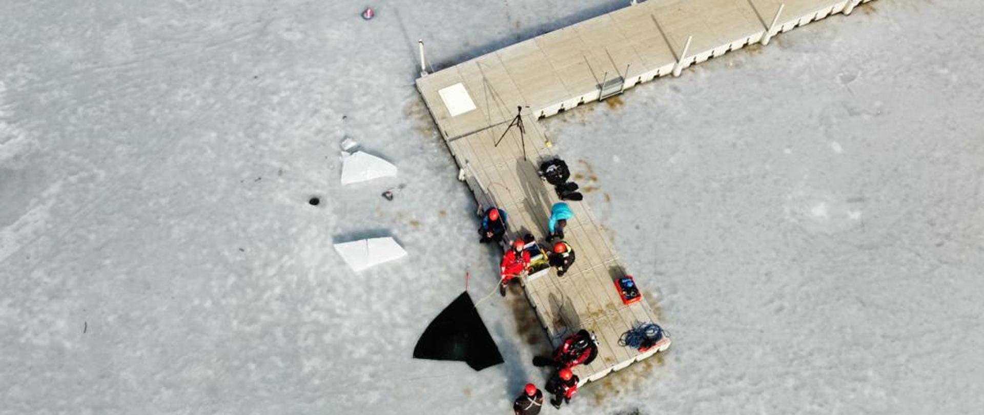 Na zdjęciu z lotu ptaka widać strażaków podczas szkolenia z nurkowania pod lodem.