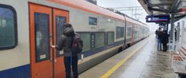 Pasażer wsiada do pociągu na zmodernizowanej stacji Kraków Bieżanów