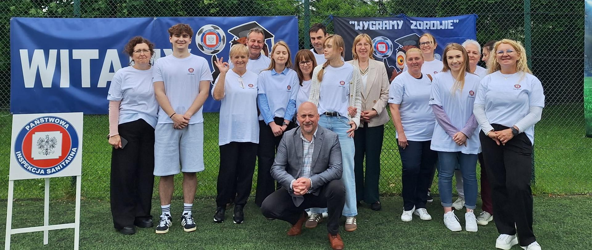 Osoby pozujące do wspólnego zdjęcia na boisku piłkarskim
