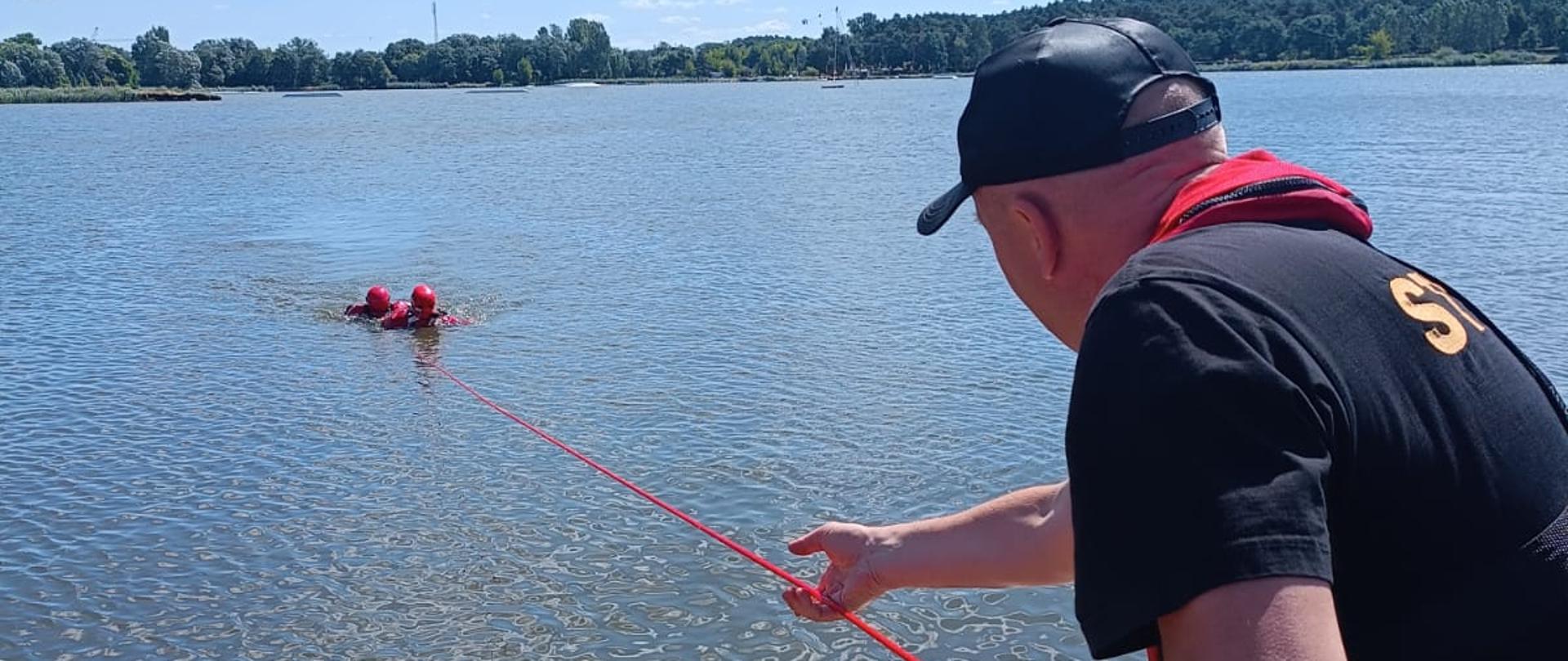 Strażak z liną w ręku ewakuujący poszkodowanego z wody