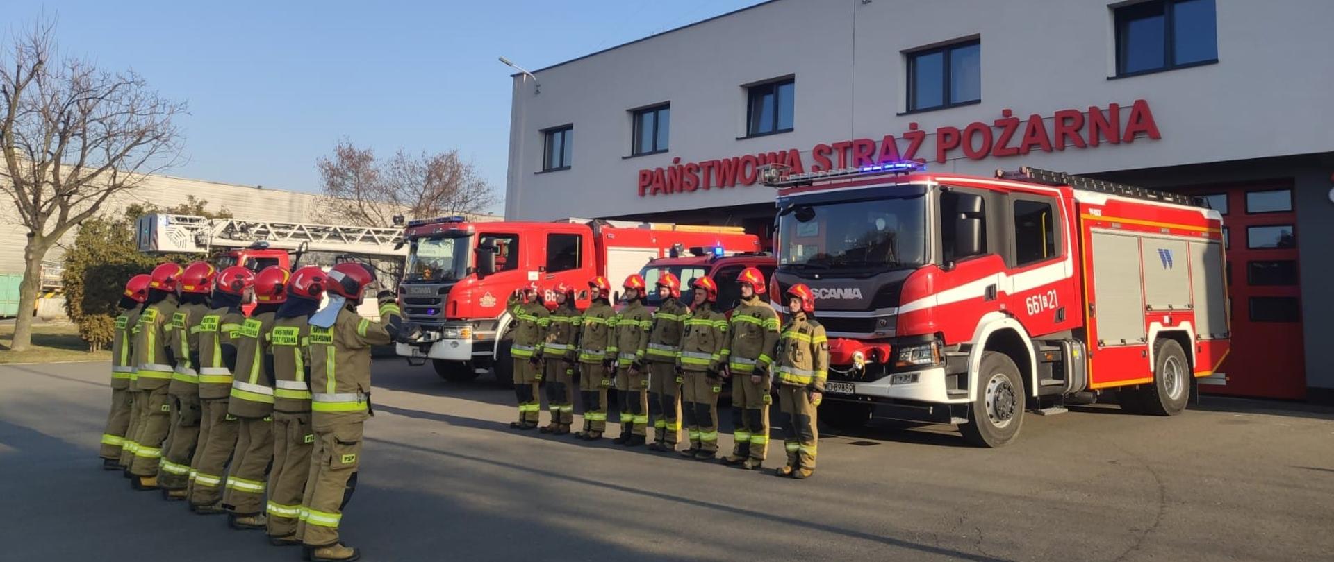 Na zdjęciu zbiórka strażaków oddających hołd poległym strażakom z Ukrainy. W tle samochody strażackie oraz budynek JRG.