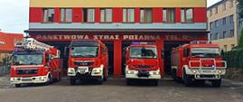 Kolorowa fotografia przedstawia cztery czerwone pojazdy bojowe straży pożarnej przed bramami garażowymi. Pojazdy mają włączone sygnały świetlne. W tle ściana frontowa budynku Komendy Powiatowej Państwowej Straży Pożarnej w Brzozowie. Na ścianie widoczny napis Państwowa Straż Pożarna tel. 998.