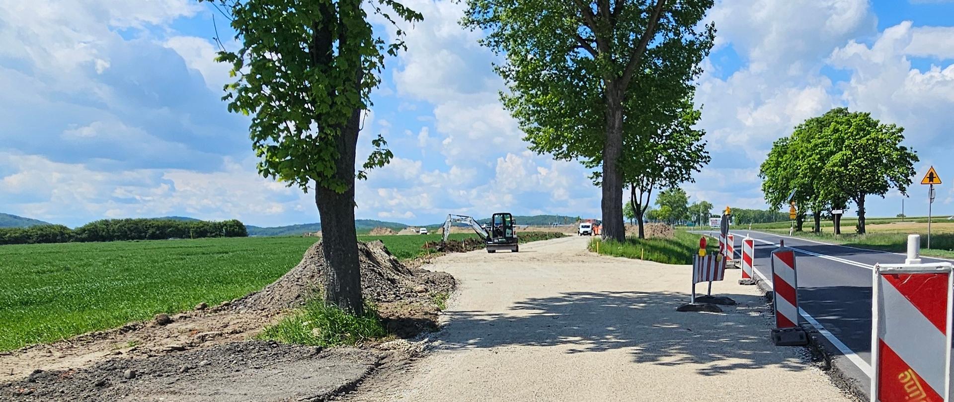 Prace na rozbudowie skrzyżowania. Widać koparkę i drogę tymczasową.