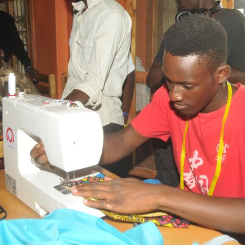 Chłopiec uczy się szyć na maszynie pod okiem nauczycieli