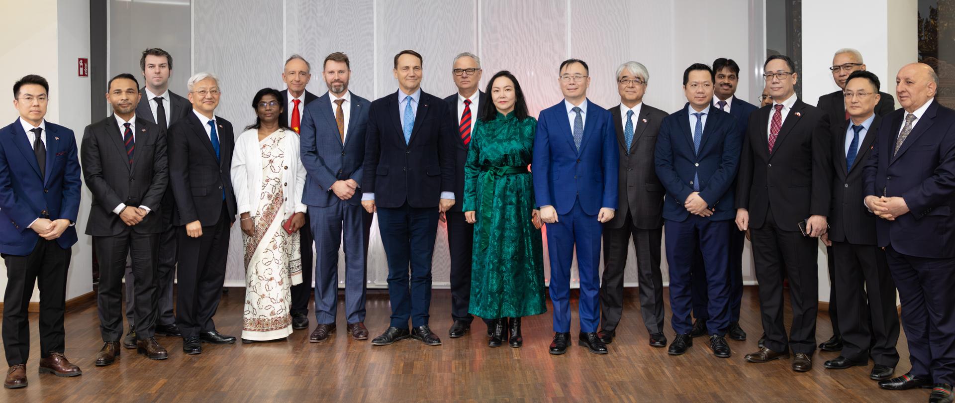 Grupa osób stojąca w kolorowych strojach. 