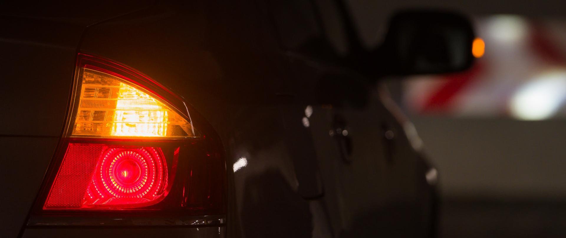 Na zdjęciu na oświetlenie z tyłu samochodu osobowego, a na pierwszym planie włączony kierunkowskaz