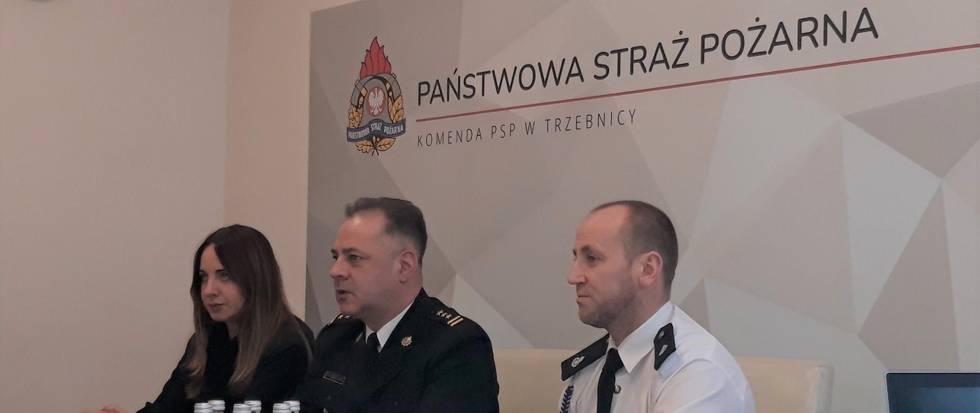 Komendant Powiatowy z Prezesem ZOSP RP i Starosta Powiatowym przy siedzący przy stole patrzący na ekran wideokonferencji