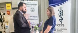 mężczyzna i kobieta rozmawiają przed stolikiem z gadżetami , w tle baner z logo PIORiN 
