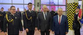 Wręczenie aktu nadania stopnia ogniomistrza funkcjonariuszowi mł. ogn. Igorowi Gałan. Wręczenia dokonali Zastępca Pomorskiego Komendanta Wojewódzkiego PSP bryg. Wojciech Berent, Wicewojewoda Pomorski Pan Mariusz Łuczyk, Poseł na Sejm RP Pan Aleksander Mrówczyński. W tle strażacy stoją w dwuszeregu.