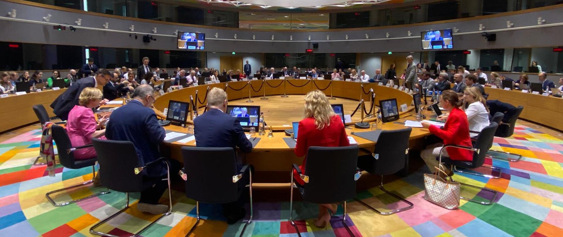 Spotkanie Rady Unii Europejskiej w sali konferencyjnej w Brukseli. Delegaci z państw członkowskich siedzą przy okrągłym stole, prowadząc obrady. 