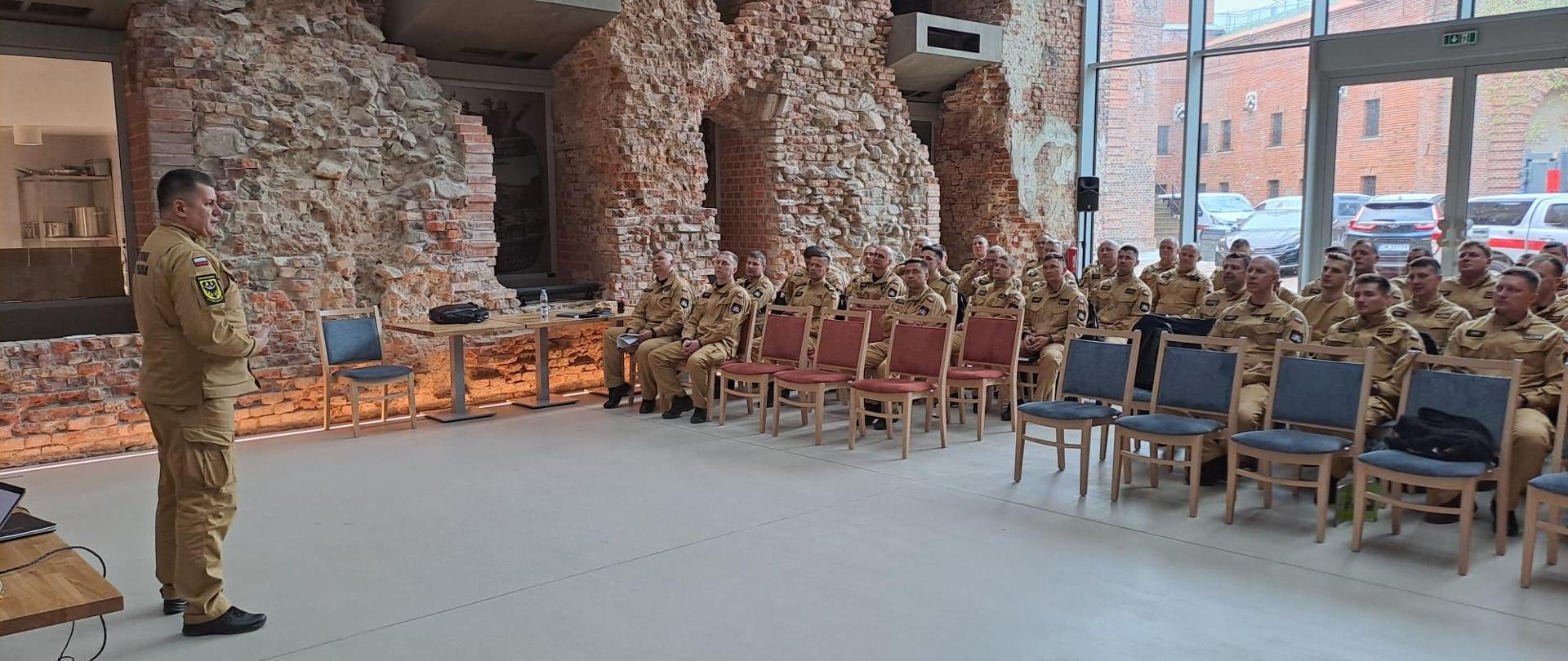 Strażacy w umundurowaniu służbowym podczas szkolenia.