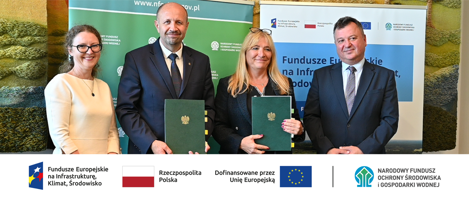 Na zdjęciu na tle banera z logo Narodowego Funduszu Ochrony Środowiska i Gospodarki Wodnej stoi od lewej: koordynator umowy Anna Siwek, Zastępca Prezesa Narodowego Funduszu Ochrony Środowiska i Gospodarki Wodnej Robert Gajda i prezes Przedsiębiorstwo Wodociągów i Kanalizacji "WODNIK" Katarzyna Wierska-Kuberska oraz Zastępca Dyrektora Departamentu Adaptacji do Zmian Klimatu Robert Markiewicz. Prezes Gajda i Prezes Wierska-Kuberska trzymają w dłoniach podpisaną umowę.