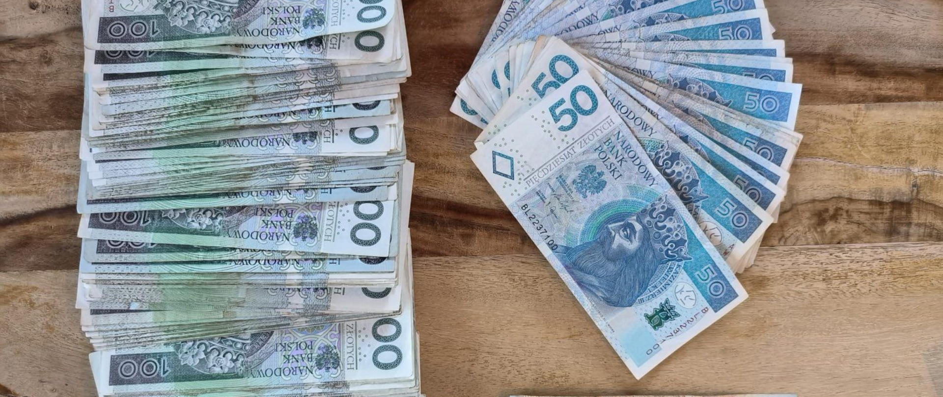 Na stole rozłożone banknoty o nominałach 50 zł, 100 zł i 200 zł