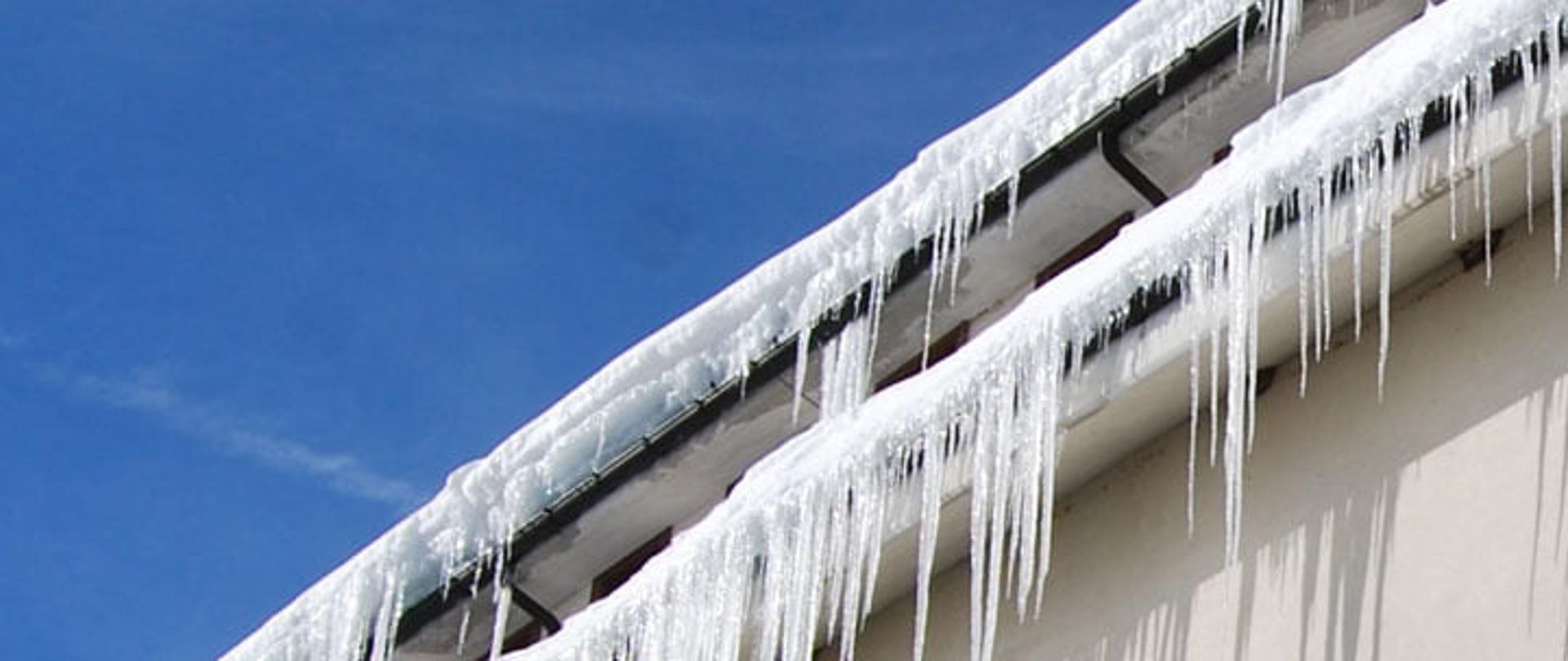 Zdjęcie przedstawia zwisające z krawędzi dachy sople.