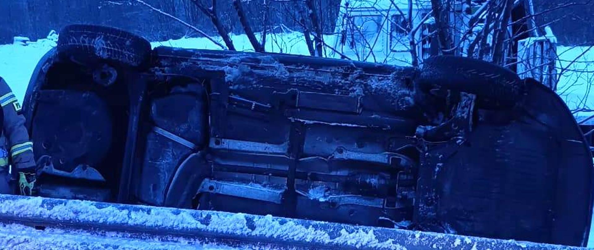 Samochód osobowy leżący na boku poza drogą