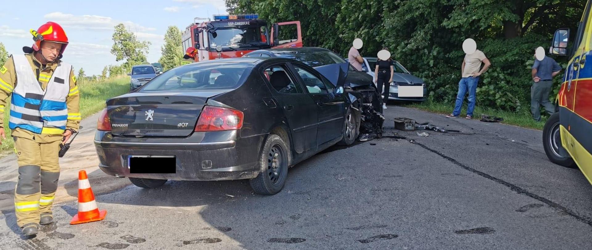 Zdjęcie przedstawia strażaków prowadzących działania ratownicze w obrębie wraków pojazdów. 
