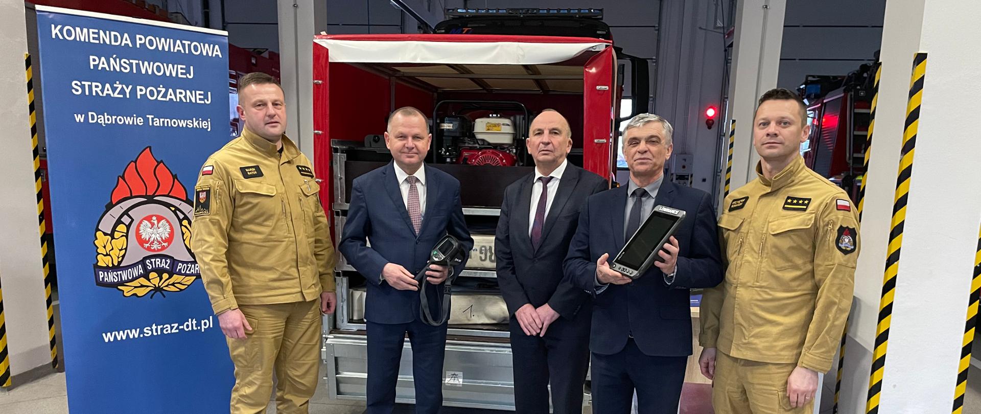 Na zdjęciu osoby przekazujące sprzęt oraz strażacy