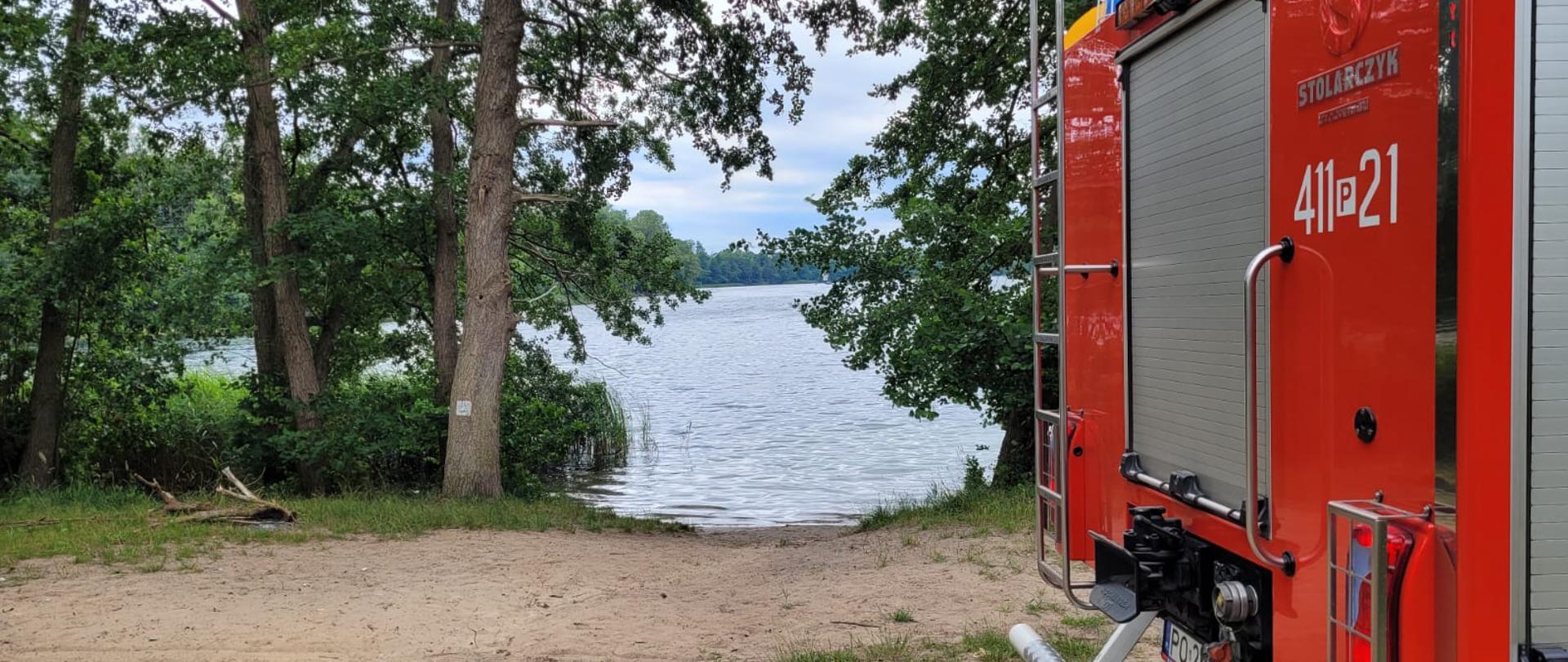 Samochód pożarniczy a w tle jezioro.
