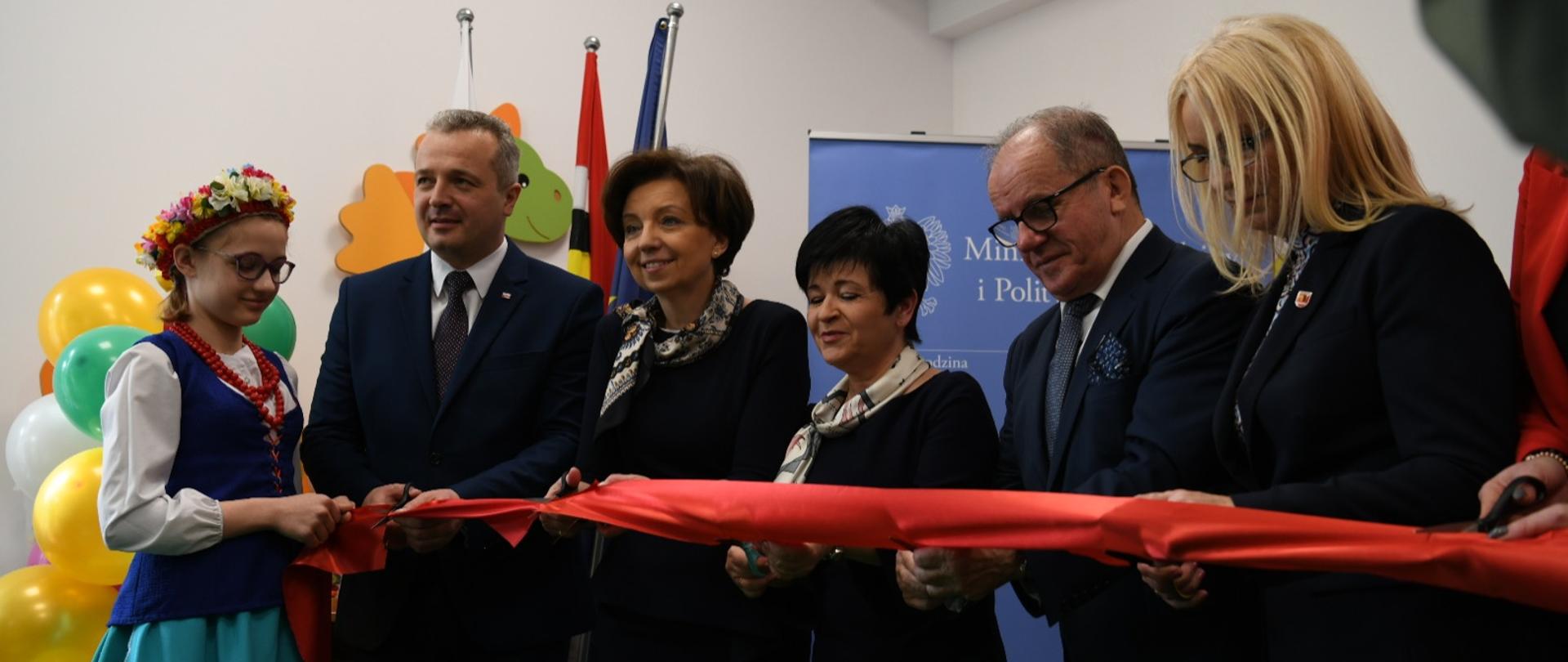 Na zdjęciu grupa osób przecinających czerwoną wstęgę, jako symbol otwarcia nowej placówki.