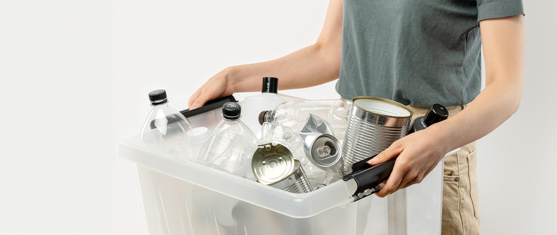 Człowiek trzymający plastikowy kosz ze śmieciami