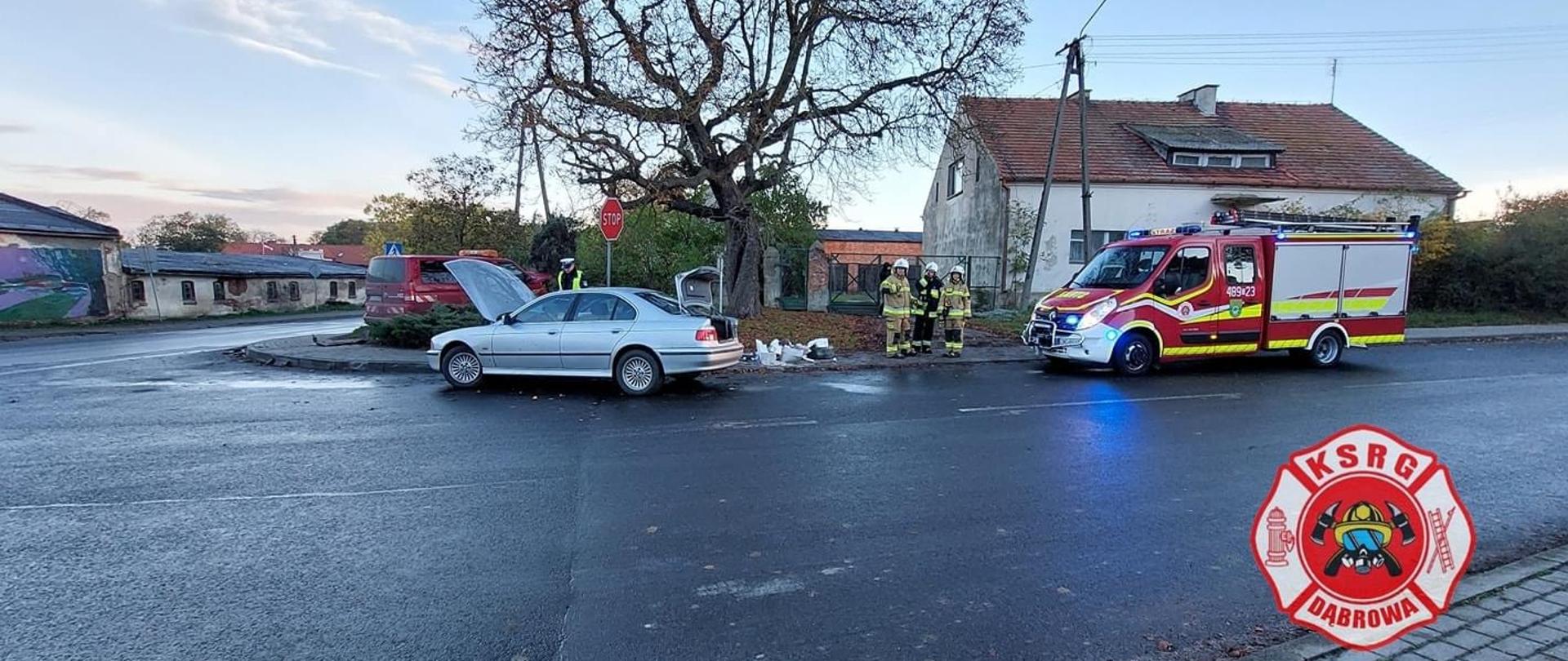 Po prawej stronie stoi samochód strażacki. Po lewej stronie stoją samochody biorące udział w kolizji.