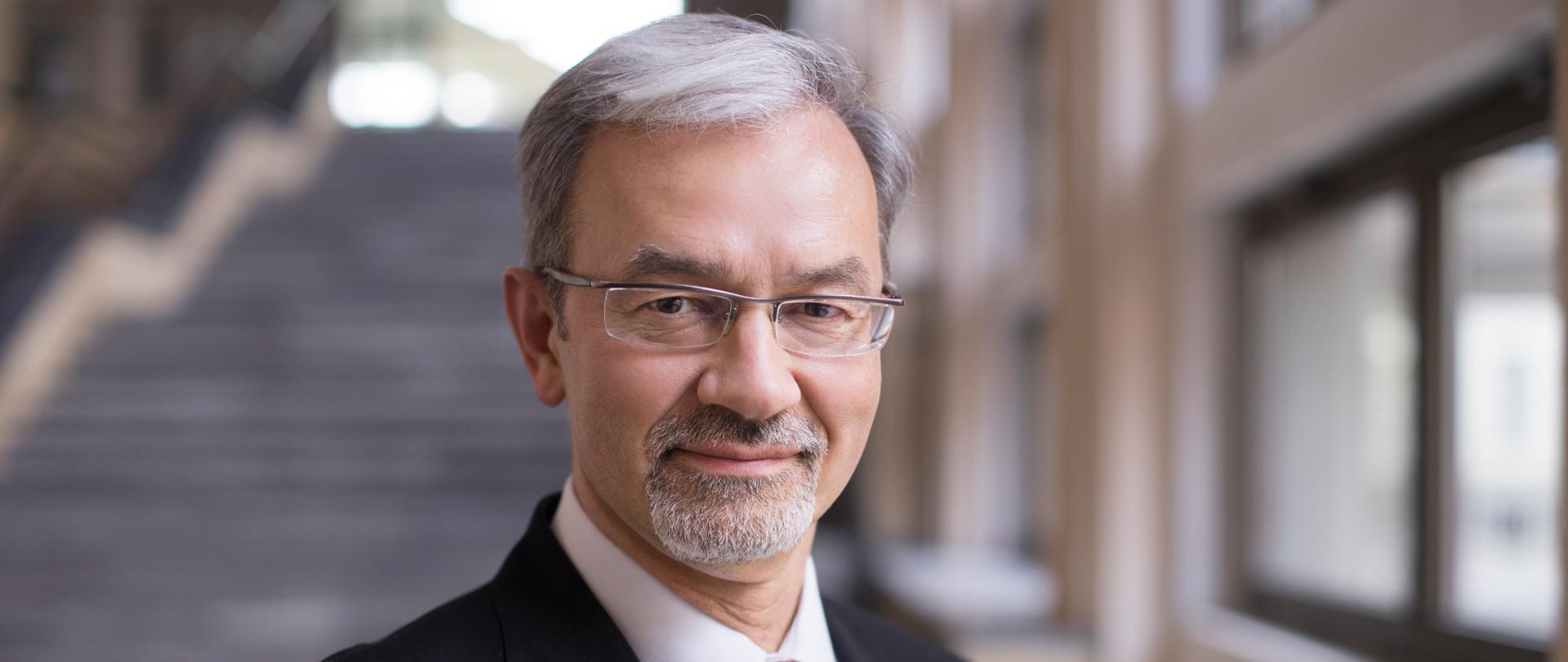 Minister Jerzy Kwieciński stoi w budynku na tle schodów