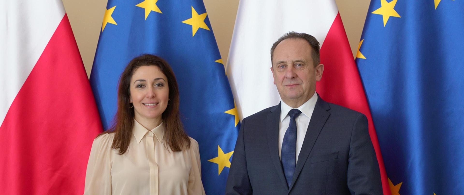 Minister Andrzej Gut-Mostowy oraz Ambasador Azerbejdżanu Nargiz Gurbanova stoją na tle flag Polski i Unii Europejskiej