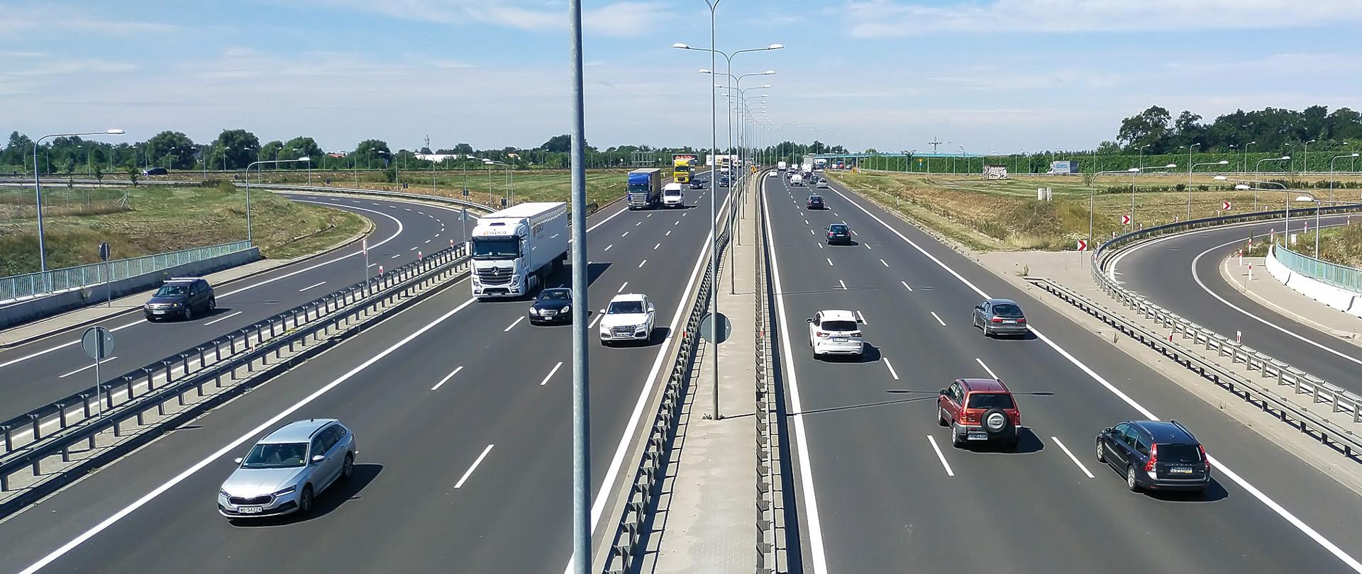 Pojazdy poruszające się po drodze ekspresowej S2 w Warszawie. Gęsty ruch pojazdów poruszających się trzema pasami w obu kierunkach.