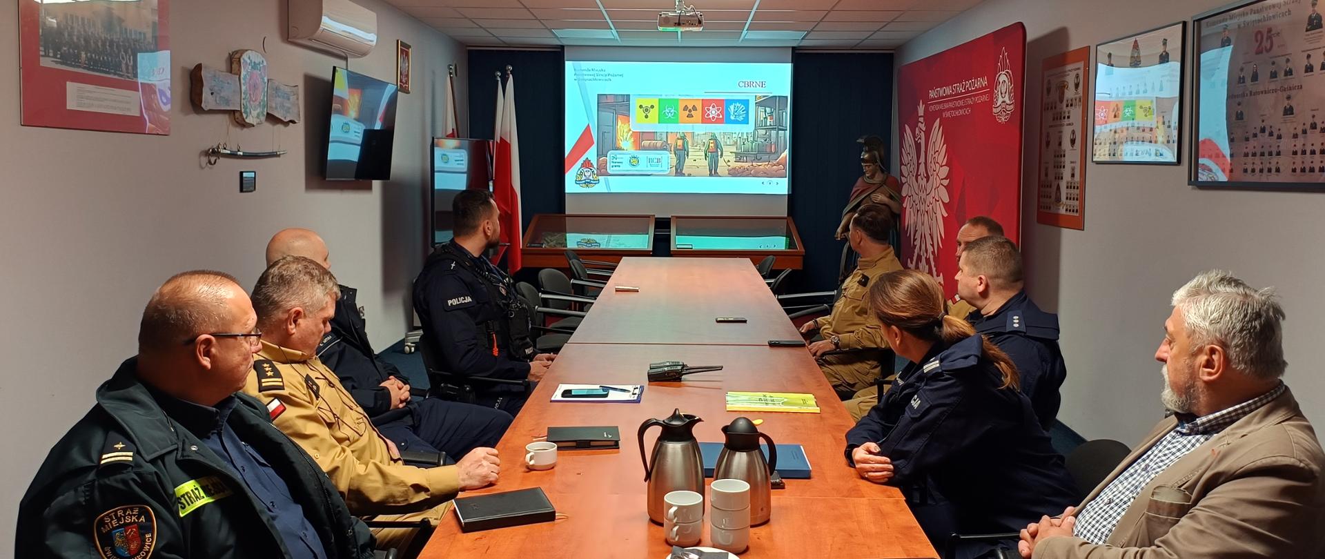 W sali narad odbywają się warsztaty dla kierowników służb, którzy zapoznają się z prezentacją dotyczącą ćwiczeń.