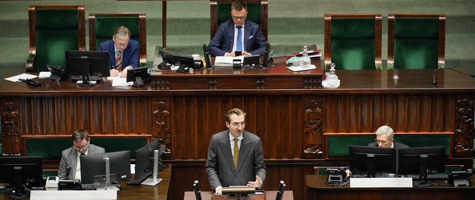 Wiceminister funduszy i polityki regionalnej Jan Szyszko stoi na mównicy sejmowej i przemawia

