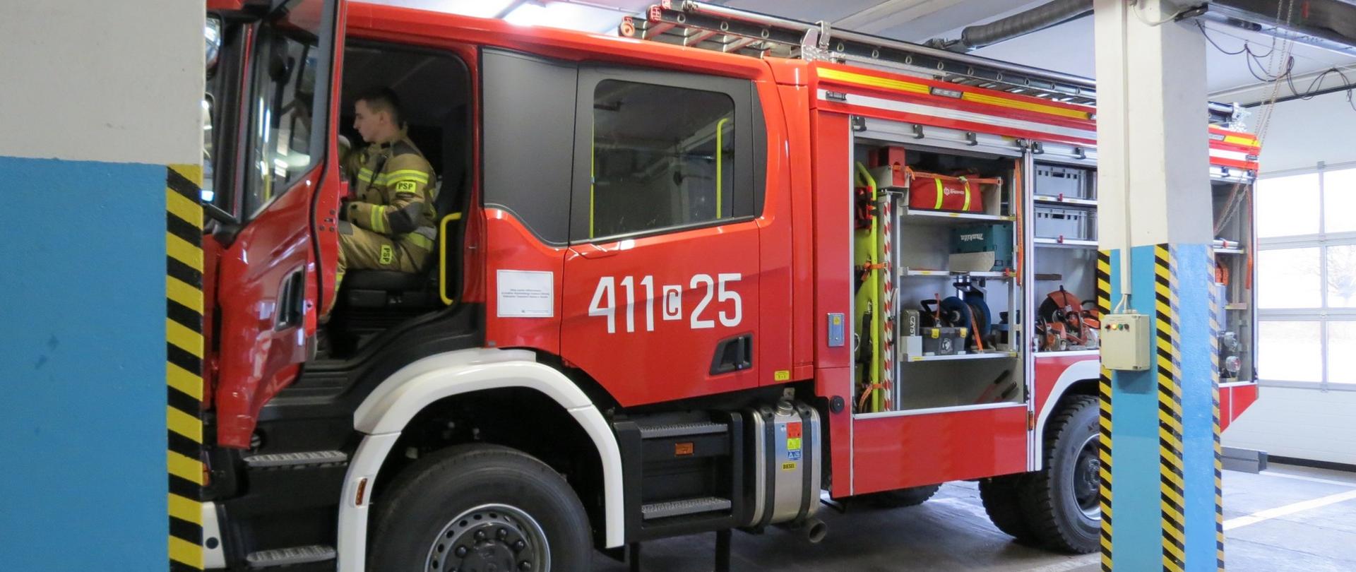 Zdjęcie przedstawia nowy ciężki samochód ratowniczo-gaśniczy SCANIA w pomieszczeniu garażowym.