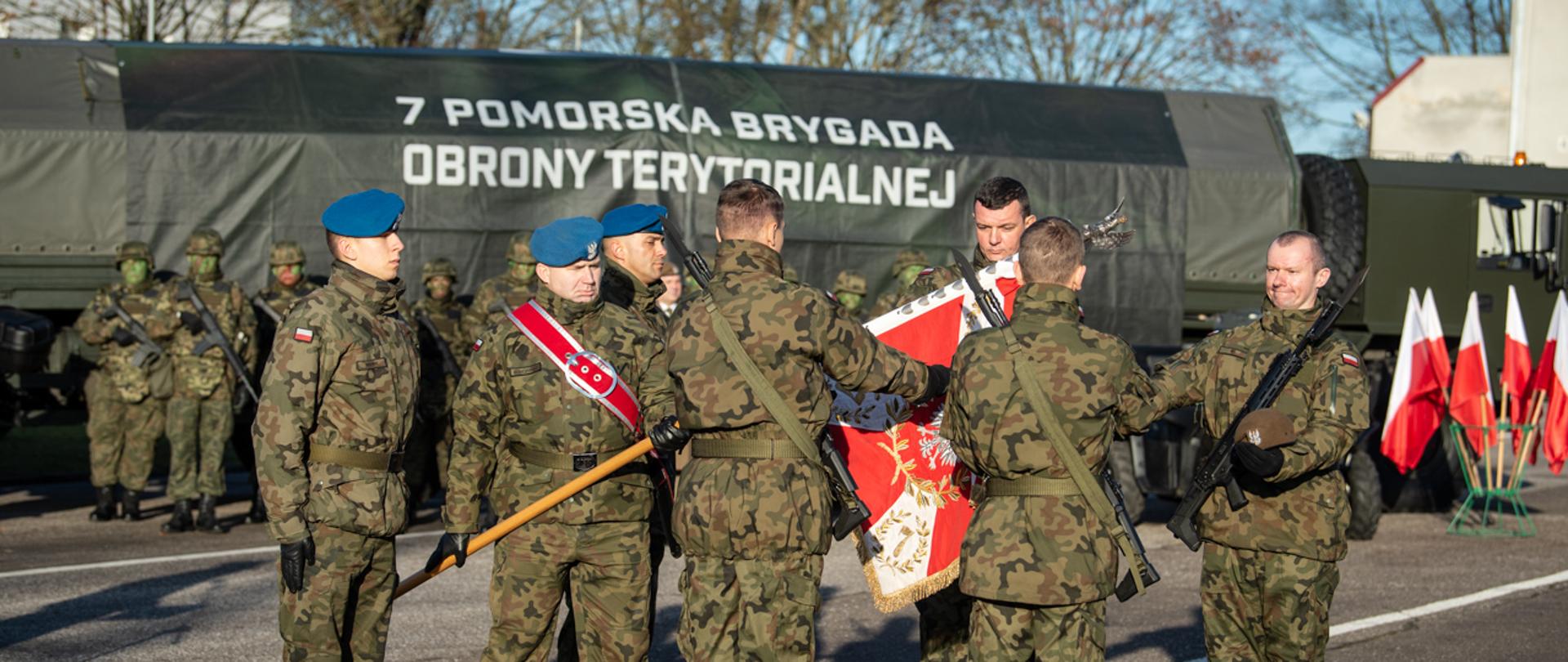 Żołnierze składają przysięgę stojąc przed sztandarem.