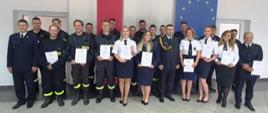 Stojący w dwóch rzędach strażacy pozujący do zdjęcia, w rękach trzymają zaświadczenia o ukończeniu kursu