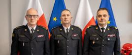 Na zdjęciu widzimy trzech strażaków w mundurach wyjściowych. Pozują do zdjęcia od lewej mężczyzna w okularach w stopniu brygadiera PSP, w środku mężczyzna w stopniu starszego brygadiera PSP, po prawej nadbrygadier PSP,