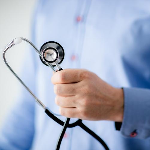 Dłoń mężczyzny w niebieskiej koszuli ze stetoskopem