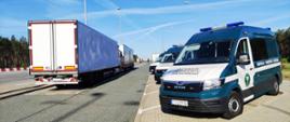 Kontrole przeprowadzone przez inspektorów lubuskiej Inspekcji Transportu Drogowego. Po lewej zatrzymane samochody ciężarowe, po prawej inspekcyjne furgony zaparkowane na parkingu przy drodze.