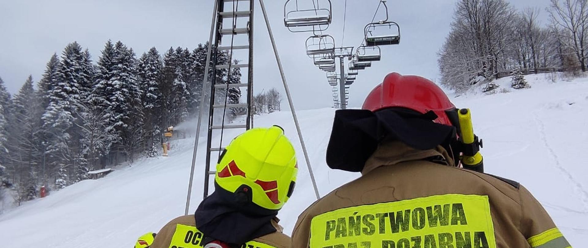 Zdjęcie przedstawia strażaków podczas ćwiczeń z ewakuacji osób z kolei linowej.