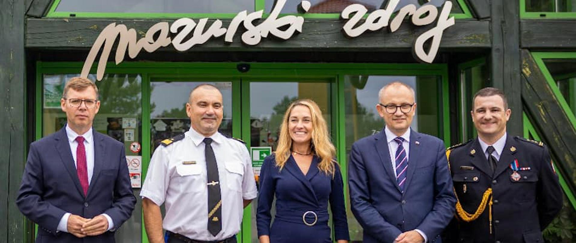 Wojewoda Warmińsko-Mazurski Artur Chojecki stoi razem z Komendantem Wojewódzkim PSP w Olsztynie nadbryg. Tomaszem Komoszyńskim, Wiceministrem Błażejem Pobożym i Panią Burmistrz Gołdapi.