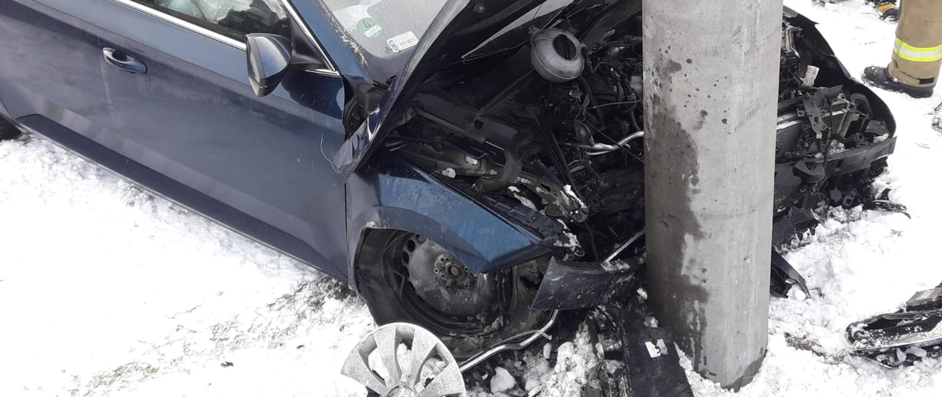Rozbity samochód stojący przy słupie.