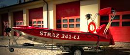 Zdjęcie przedstawia łódź przeznaczoną do ratownictwa wodnego na tle bram garażowych przy jednostce ratowniczej nr 1 w Słupsku.