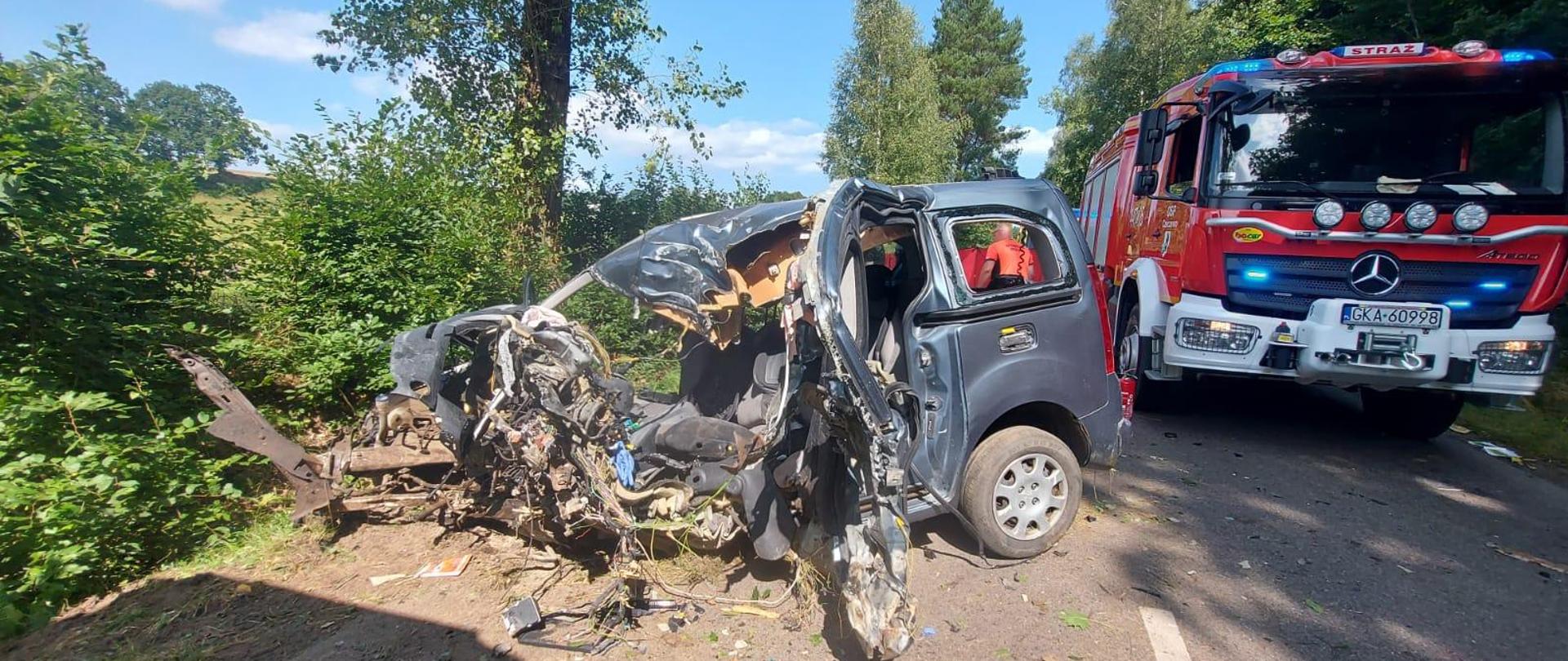 Rozbity samochód biorący udział w zdarzeniu, obok którego znajduje się samochód strażacki
