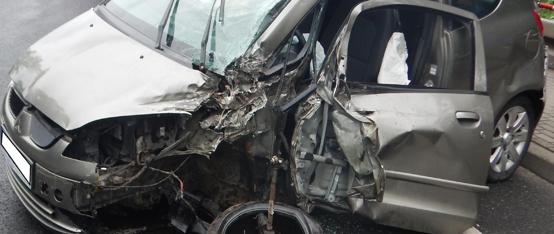 Zdjęcie przedstawia rozbity przód i bok samochodu osobowego