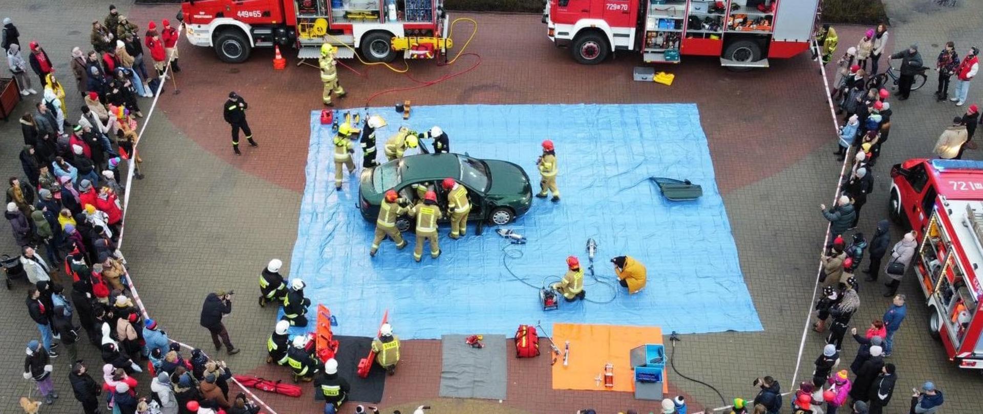 Strażacy prowadzą pokaz uwalniania osoby poszkodowanej w wypadku komunikacyjnym. 