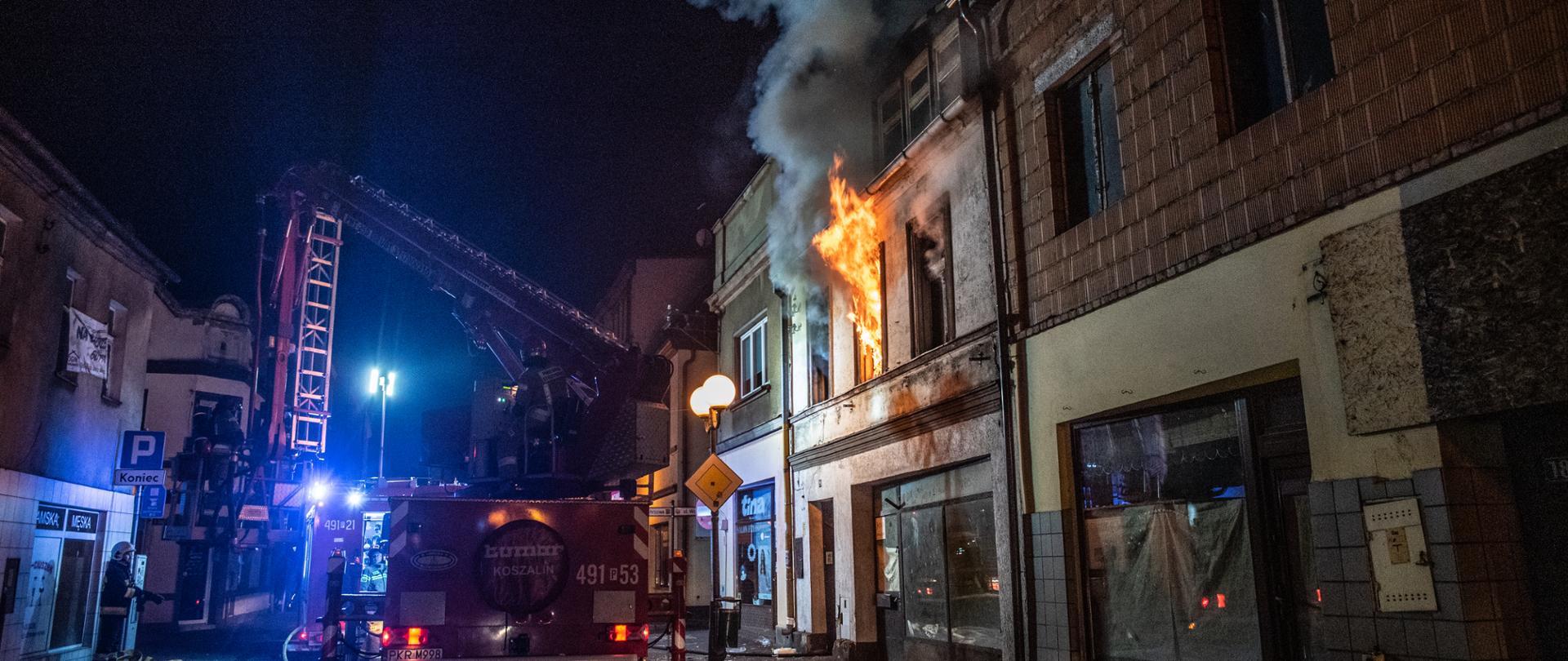 Zdjęcie przedstawia pożar kamienicy w zwartej zabudowie z okien wychodzą języki ognia