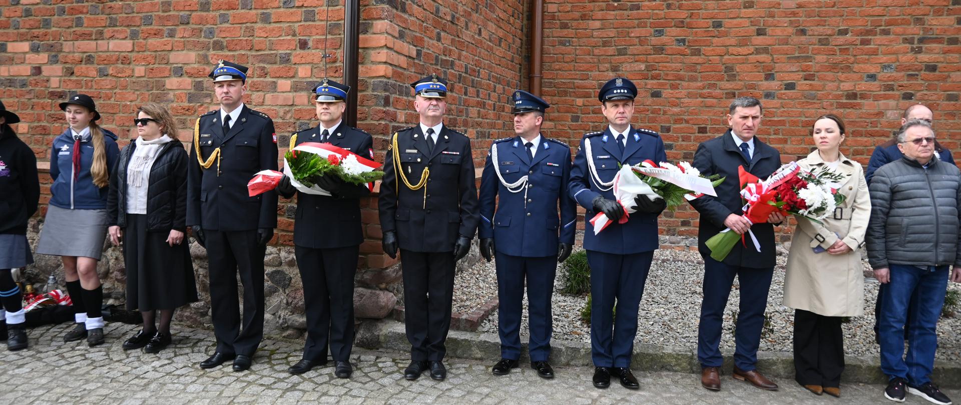 Funkcjonariusze i goście stoją przed kościołem w trakcie uroczystości.