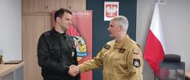 Komendant Powiatowy Państwowej Straży Pożarnej w Człuchowie st. bryg. Radosław Batruch stoi w gabinecie i wręcza akt mianowania na stanowisko zastępcy dowódcy Jednostki Ratowniczo - Gaśniczej w Człuchowie mł. kpt. Dawidowi Machnio. 