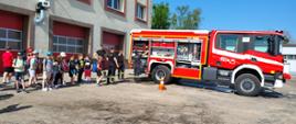 Zdjęcie przedstawia grupę szkolną , której strażacy JRG KP PSP Kłobuck pokazują wyposażenie samochodu pożarniczego