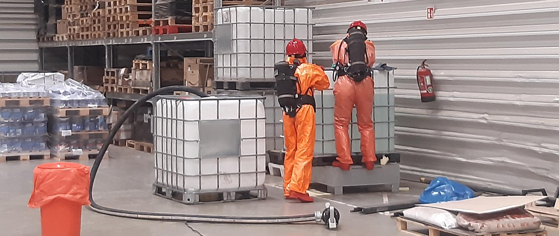 Na zdjęciu strażacy w środkach ochrony indywidualnej w trakcie przygotowania do przepompowania niebezpieczej substancji ze zbiornika