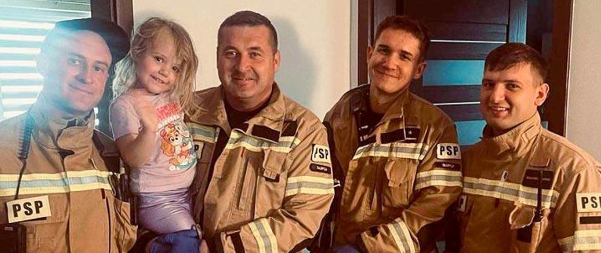 strażacy na zdjęciu z trzyletnią dziewczynką