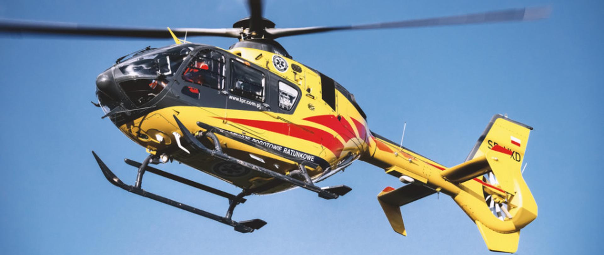 na całym zdjęciu helikopter lotniczego pogotowia ratowniczego na tle niebieskiego nieba